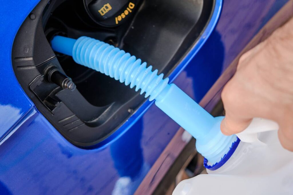 Close up filling of diesel exhaust fluid/adblue from canister into the tank of blue car for reduction of air pollution. Environmental or eco friendly solution.